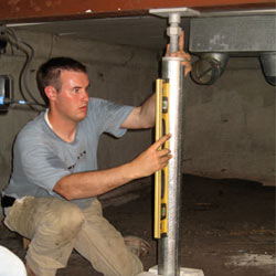 A contractor in Cody installing a crawl space jack post.