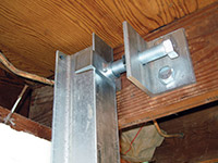 Securing the i-beam system to the top of the floor joist in a foundation wall repair in Riverton.