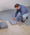 Contractors installing basement subfloor tiles and matting on a concrete basement floor in Sheridan, Wyoming