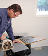 installing a waterproof vapor barrier on a basement floor to prepare for basement carpeting in a Laramie home
